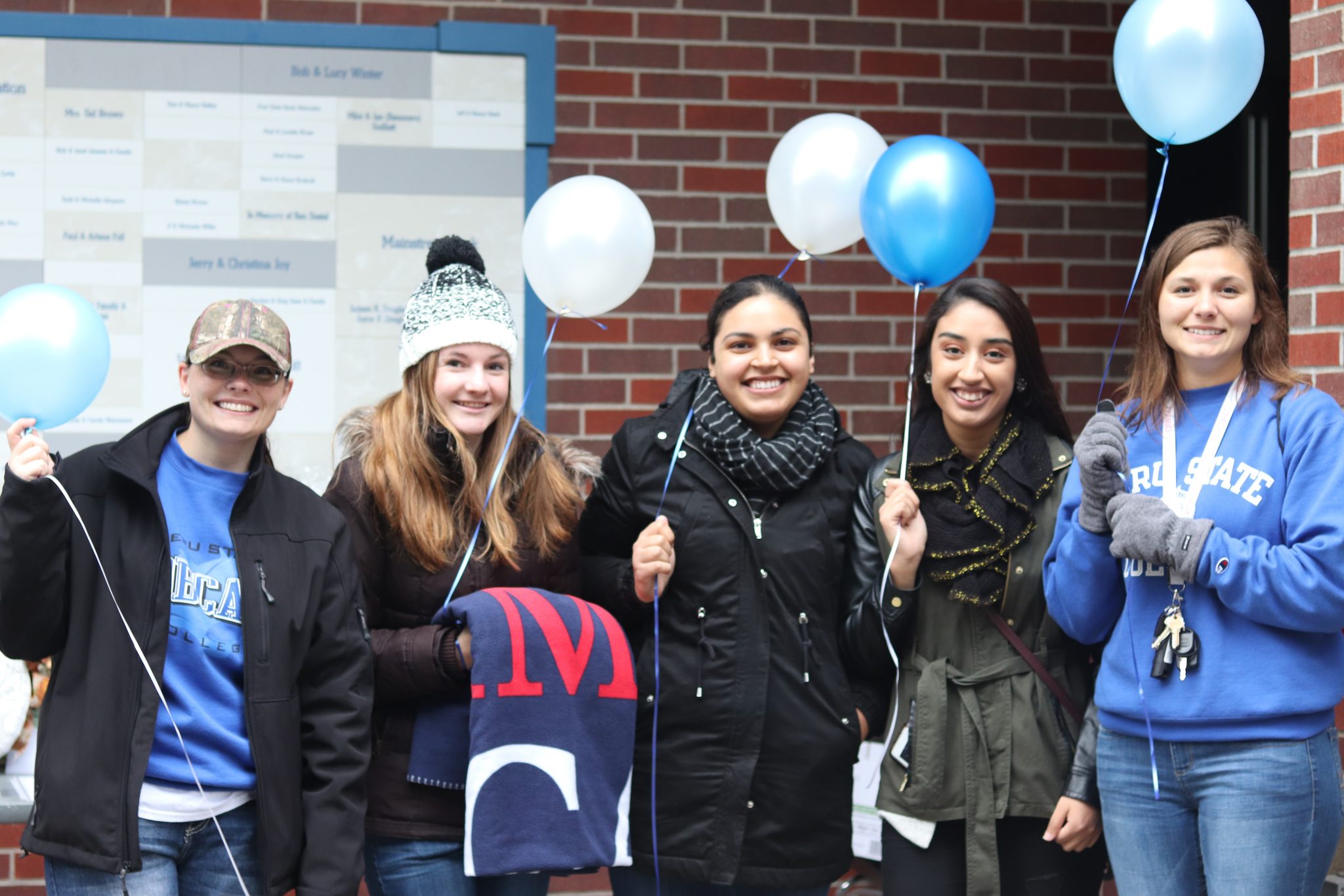 students holding blue and white balloons